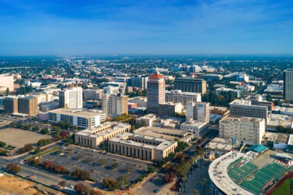 Aerial skyline view of Downtown Fresno during Autumn centered on the Pacific Southwest Building, with a hazy sky and skyline in the distance.